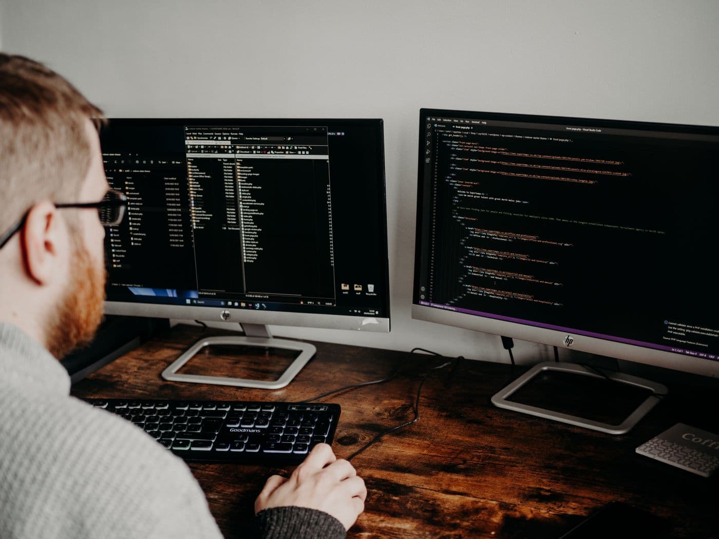 Software engineer working across two computer monitors